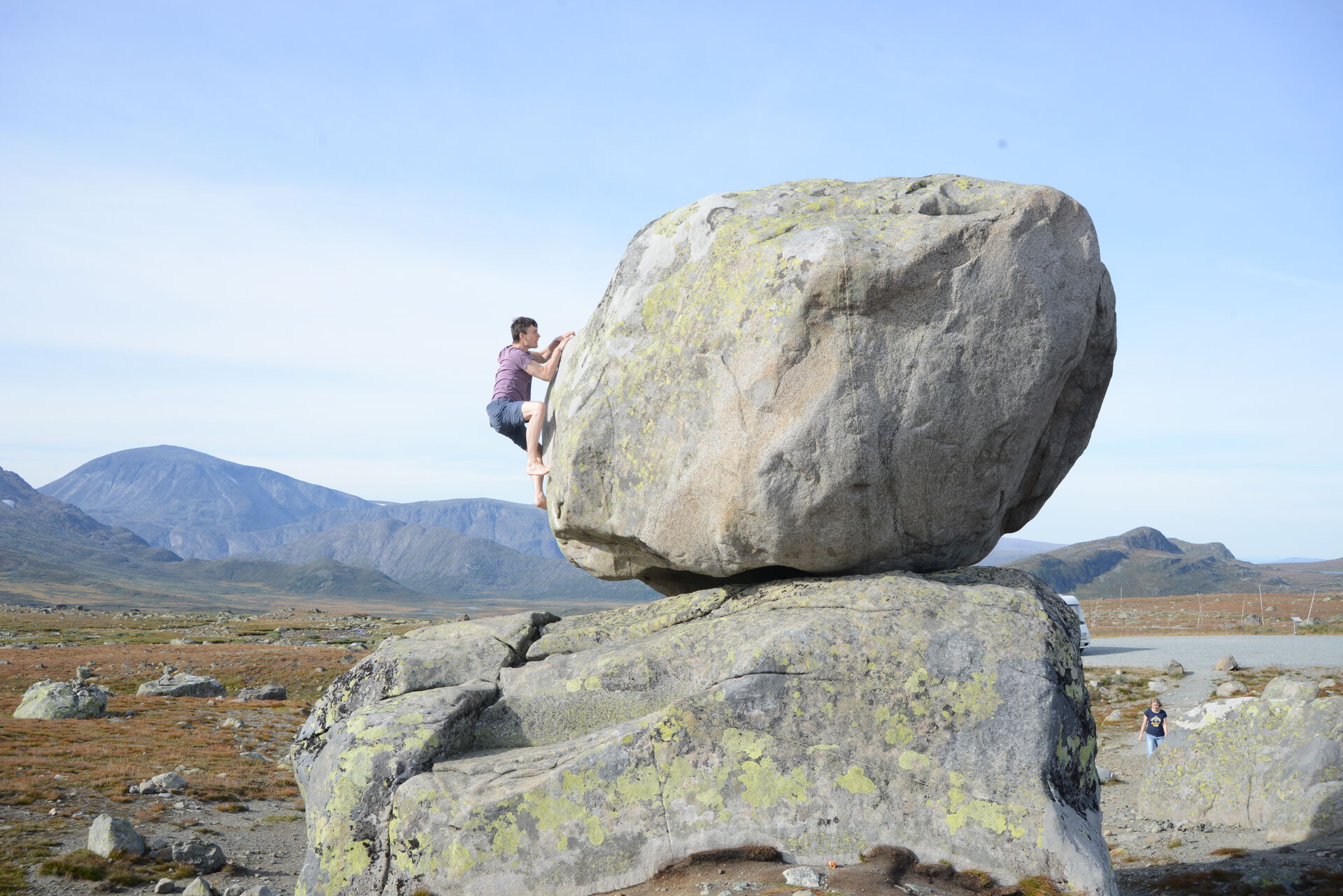 photo of a young man climbing a big rock