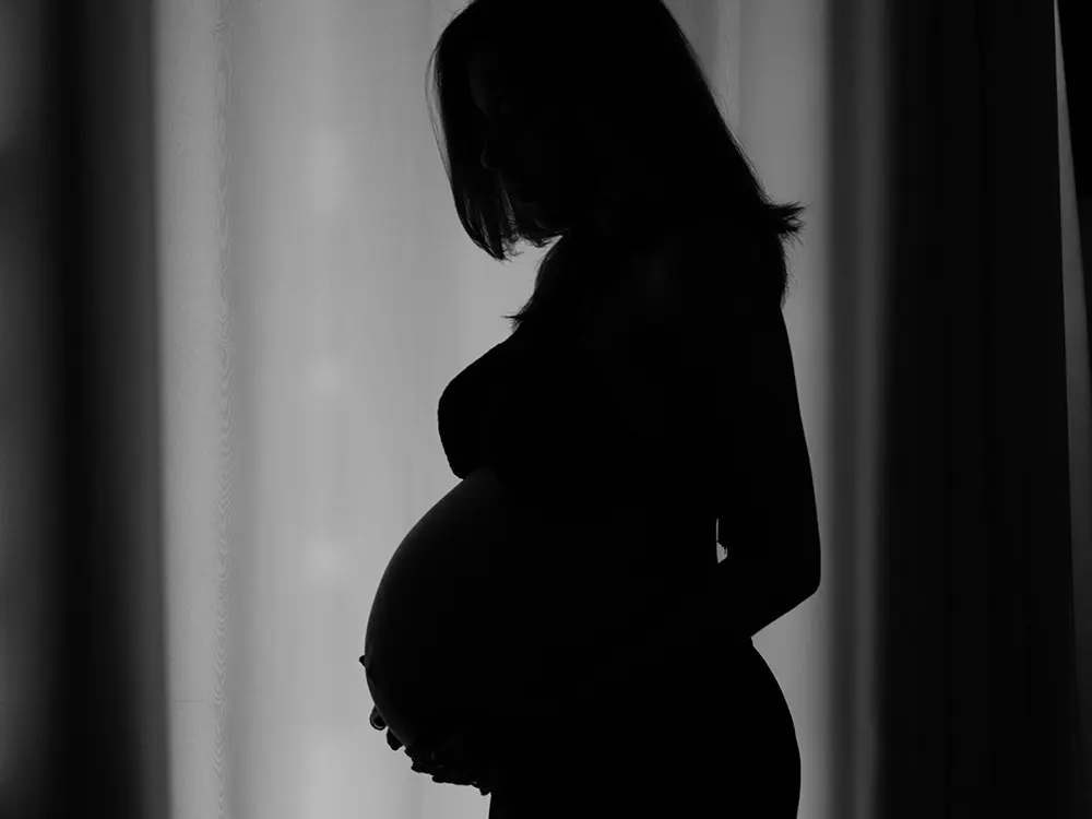 Silhuett av gravid kvinne mot ein lys bakgrunn