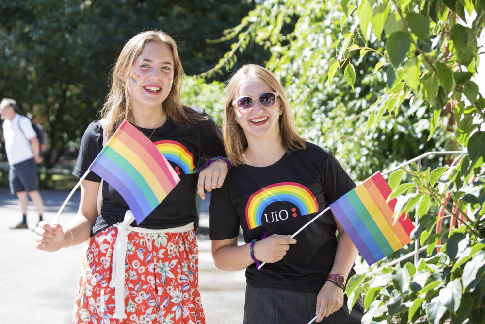 To unge kvinner med pride-flagg og UiO-t-skjorte
