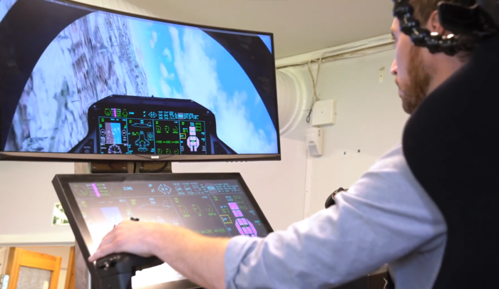 A man is piloting a virtual plane inside a flight simulator.