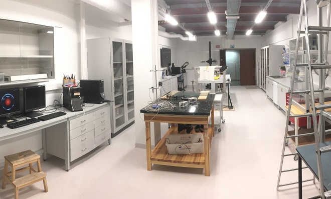 Laboratory with a computer on a desk to the left and a table with equipment in the middle.